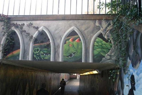 Wall Art in Exeter, with railings above and walker in tunnel beneath.