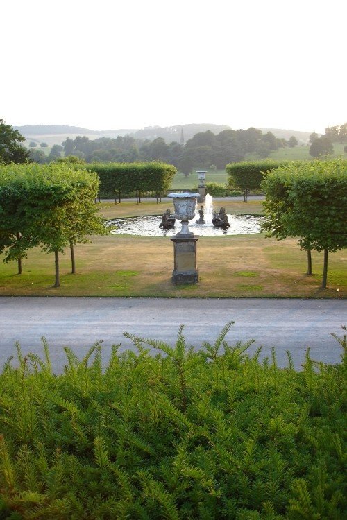 Fountain on the lawn at Chatsworth House, Derbyshire with Edensor village church in the distance