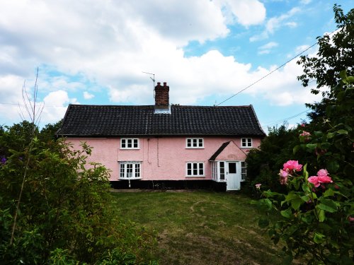 Pink thatched house on outskirts of the village