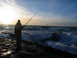 A fisherman braving the ocean on Bude Breakwater Wallpaper