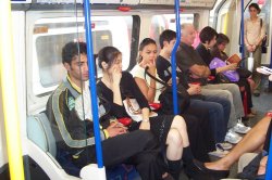 Early evening commuters travelling on Picadilly line tube between Barons Court and Hammersmith