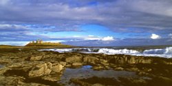 Dunstanburgh Castle, and shoreline seascape. Wallpaper
