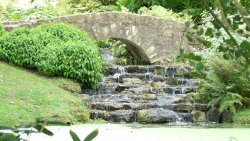 An arched bridge in the Japanese section with a waterfall Wallpaper