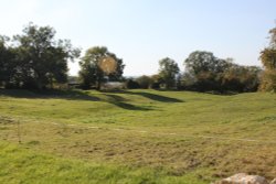 Mounds in the grass which indicate the site of the old village of Churchill Wallpaper