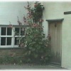 Hollyhocks grow by a cottage door.  Saffron Walden, Essex.
