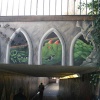 Wall Art in Exeter, with railings above and walker in tunnel beneath. - 