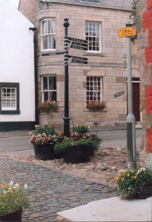Street Sign, decorated with floral tubs,showing the way to local amenities in Falkland.