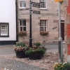 Street Sign, decorated with floral tubs,showing the way to local amenities in Falkland.