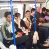 Early evening commuters travelling on Picadilly line tube between Barons Court and Hammersmith