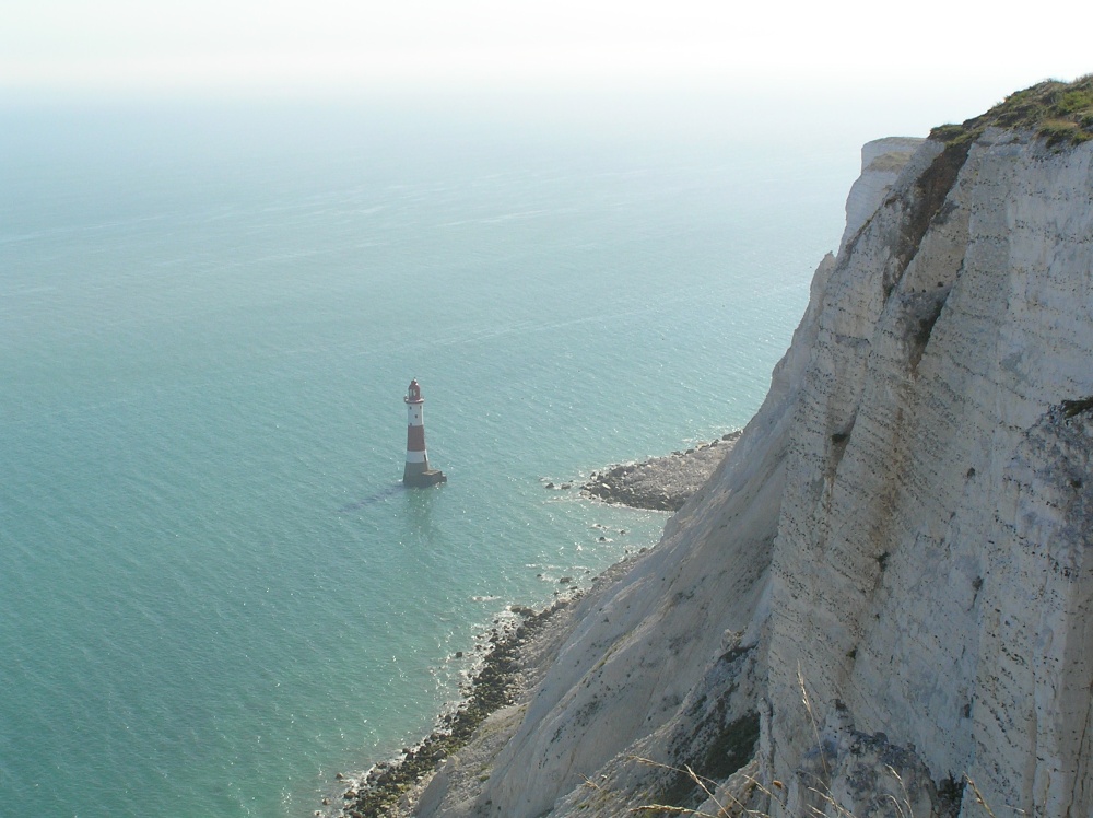 The lighthouse at Beachy Head, East Sussex, dwarfed by the while cliffs above it.