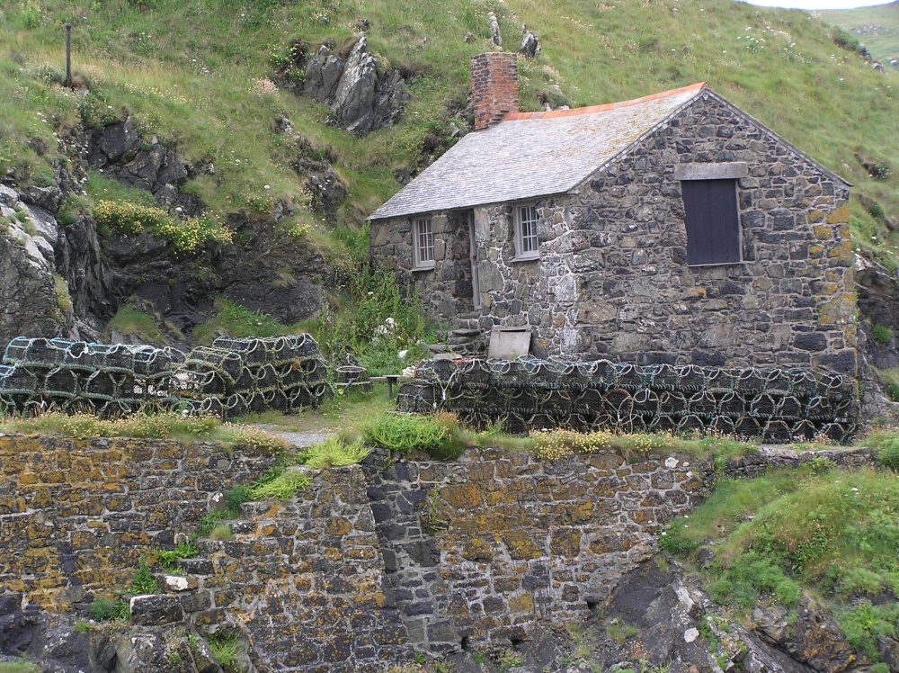 Fisherman's hut and lobster pots line the harbour wall at Mullion Cove, the Lizard, Cornwall.