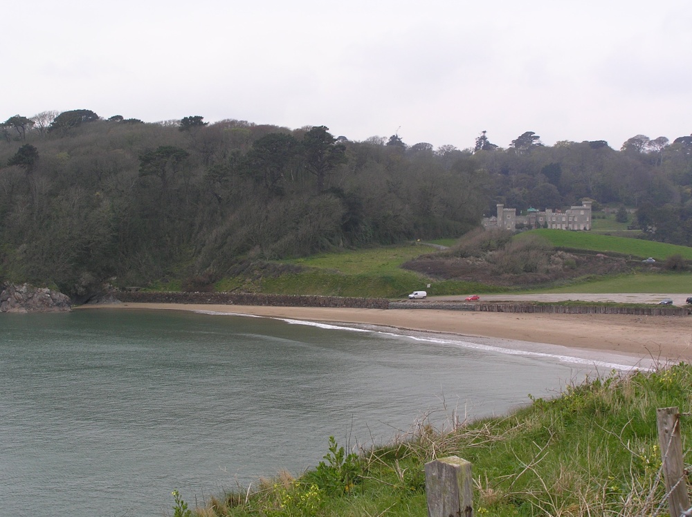 Caerhays Castle, tucked in against the tree-filled gardens behind it, overlooks Porthluney Beach photo by Hilary Hoad