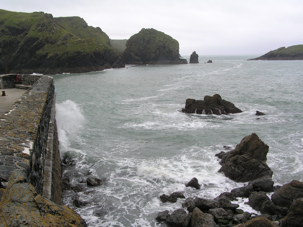 Waves break against the harbour wall at Mullion Cove, Cornwall