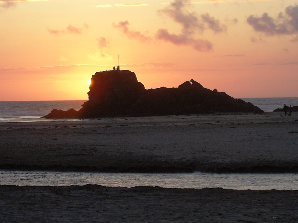 The sun behind the rocks at Perranporth