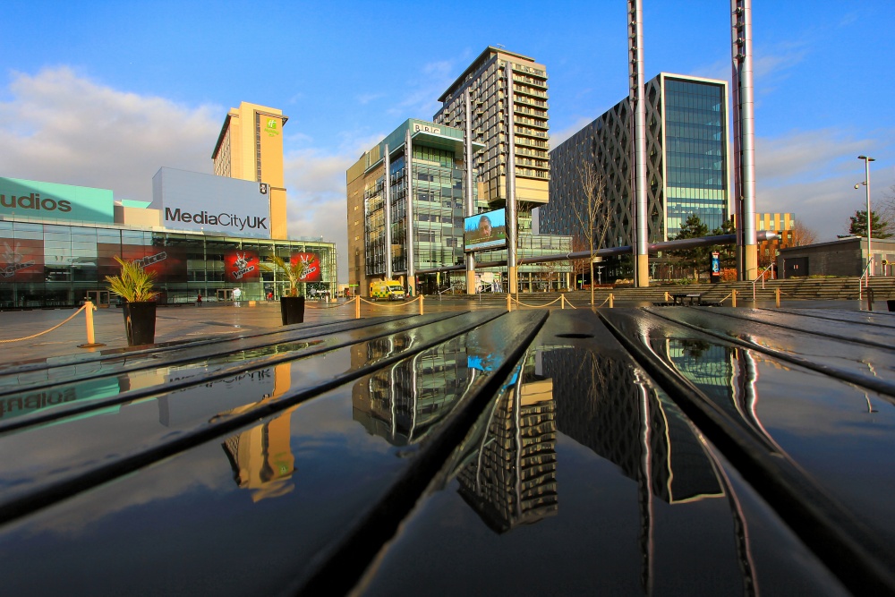 Photograph of Media City, Salford Quays, a reflection on a picnic bench.