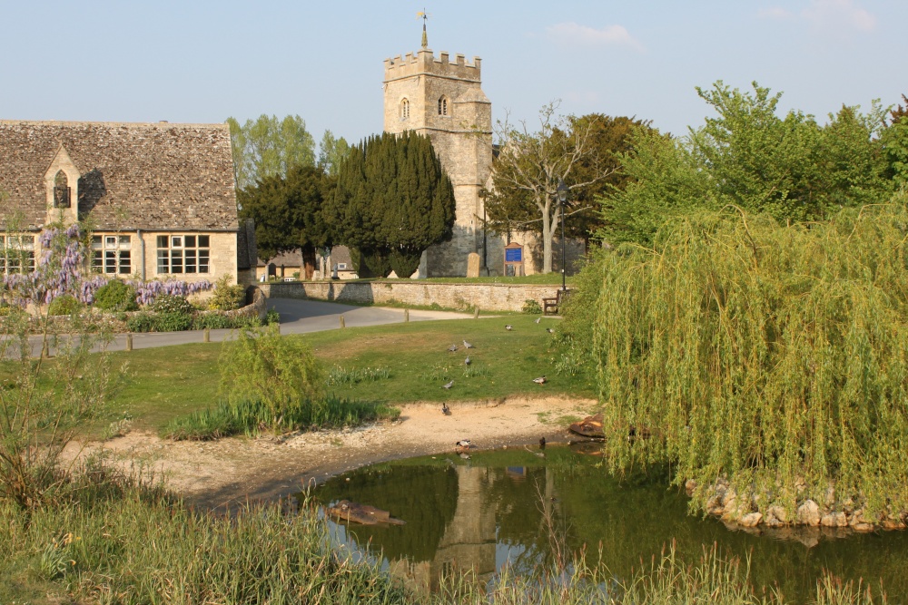 Photograph of The duck pond, Ducklington, with St. Bartholomew's Church behind